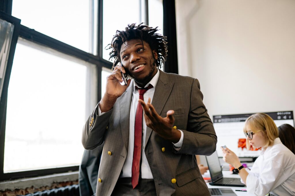 Entry-level salesman on the phone in an office with colleagues working behind